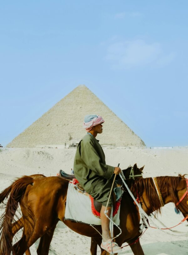 A man rides a horse against the iconic backdrop of the Giza Pyramid, Egypt.